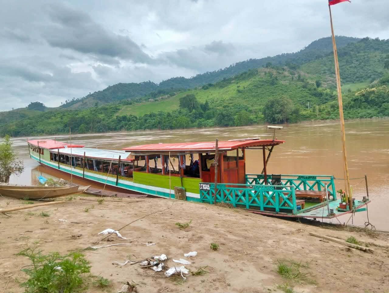 Green and red slow boat moored on a Mekong sandbank