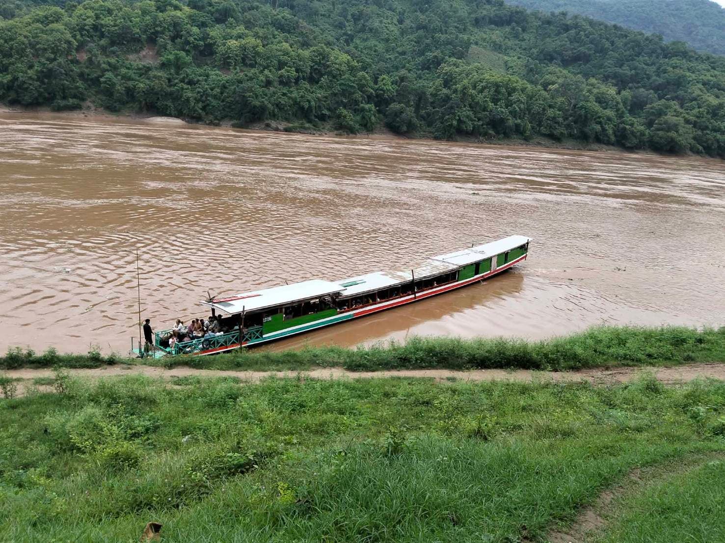 Passengers on the open bow of a Mekong slow boat